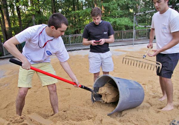 Pi Kappa Alpha Vice President Matt Tucker, sophomore in environmental technology, shovels sand into a bucket while Dave Gragnolati, senior in mechanical engineering, supervises the volleyball court setup at the Delta Sigma Phi house Thursday. Pi Kappa Alpha and Delta Sigma Phi members were spreading new sand on the court for Saturday&#8217;s Jimmy V. Volleyball Tournament, and although shoveling is hard work Tucker said, &#8220;setting up is half the fun!&#8221;