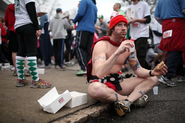 Clint Bollinger of Charlotte sits on the ground as he works on eating his dozen doughnuts during the 2010 Krispy Kreme Challenge. Photo by Matt Moore