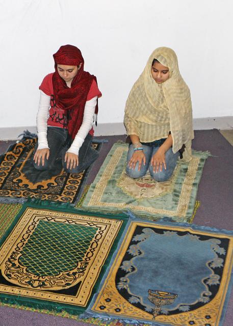 Talbia Choudhury, a junior in biochemistry, and Tahiti Choudhury, a sophomore in biological sciences, are in the fifth position of the Maghrib praying period. Muslim prayers, called salawat in Arabic, consist of multiple positions. These women pray on their prayer ruges, which are pointed toward the direction of the holy city of Mecca. Photo by Sarah Edens.