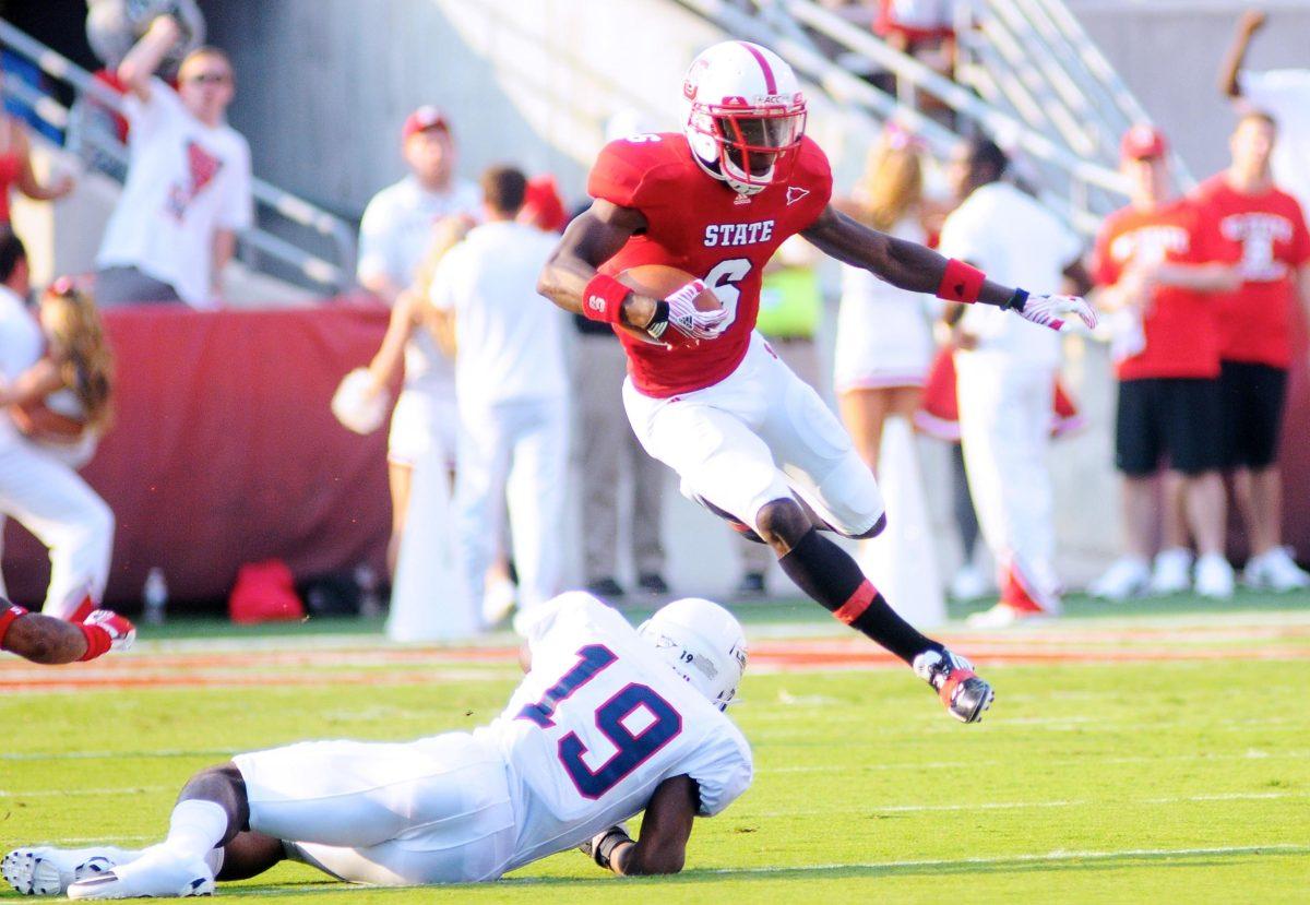 Senior wide receiver T.J. Graham leaps over Liberty's Walt Aikens during the first half of the Pack's game at Carter-Finley Stadium on Saturday. Photo by Brent Kitchen.