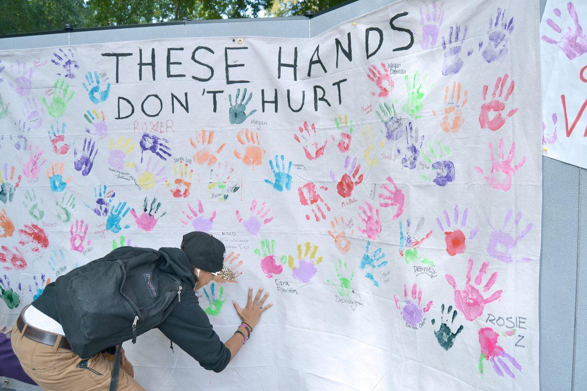 Kieyana Sutton, a senior in animal science, makes her pledge against domestic violence at the domestic violence awareness stand stating "These Hands Don't Hurt" in the brickyard on Thursday, Oct. 17, 2013. Photographed by Victoria Crocker.