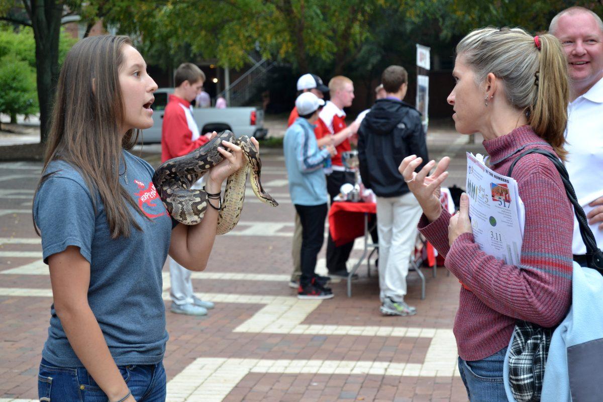 An NC State student in the Herpetology Club answers a prospective students mother's questions about the club in the brickyard at the university open house on Saturday, Oct. 19, 2013. Photographed by Victoria Crocker.