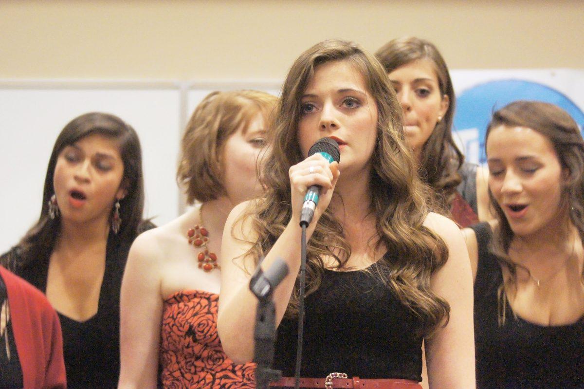 Cailin Moore, a sophomore in biological sciences, leads the Ladies in Red in a collaborative a capella performance with groups from Elon and UNC-G.