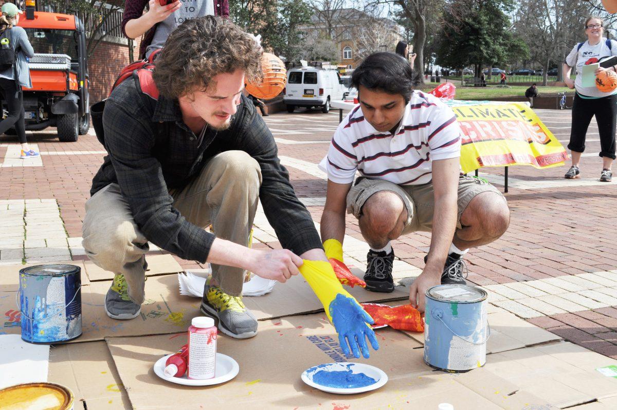 Students gathered around the Fossil's Free club's banner to paint it. Targeting Duke Energy, the purpose of this event was to show the support of the use of clean energy on campus. Photo by Elizabeth Davis