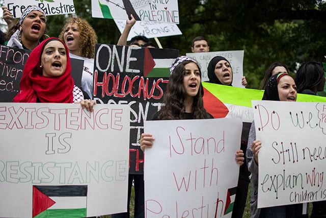 (From left to right) Sara Dahbour, Danyah Dahbour, and Khadija Ewais shout at passing cars on Morgan St. in support of the liberation of Palestine at the State Capitol Building Saturday afternoon. The protest came just a day before over one hundred Palestinians and thirteen Israeli militants were killed in the bombardment of a Gaza Neighborhood on Sunday.&#160;