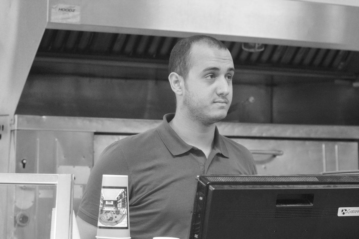 Ahmed Al-Hoory, a civil engineering graduate of Isra University in Amman, Jordan, stands at the register at his workplace I Love NY Pizza on Hillsborough Street Monday. He has been residing in North Carolina for six months and plans to take some courses to evaluate his degree next semester and then study for his master's degree the following year.