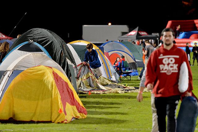 Cole Bass, freshman in design studies, sets up his tent as he prepares for the rest of the evening during Campout 2014 Friday evening on the lower Miller Field. This event was organized by Union Activities Board and it took place on Miller field on Friday. Campout, an NC State tradition, takes place every year where students gather, set up their tents, and enjoy inflatable rides. This year, every student registered for the event earned 6 loyalty points to win tickets to a football game.