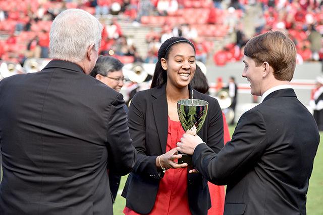 Ashley Eli, a junior studying industrial engineering and a forward on the women's basketball team, accepts the Leader of the Pack trophy from 2013 winner Austin Bath during halftime of the homecoming football game against Georgia Tech at Carter-Finley Stadium Saturday.