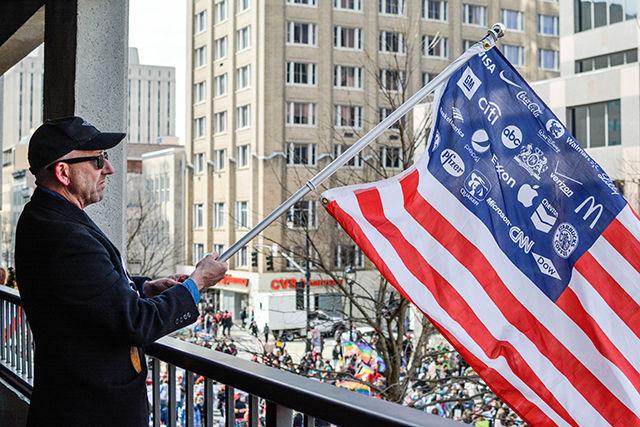Mark Edwards holds an American Flag from a parking garage at the end of the HKonJ march in downtown Raleigh. The NAACP has organized a "Mass Moral March on Raleigh" for the past nine years and continued to do so this year. Several thousand people showed up to fight for issues such as more money for public schools and a higher minimum wage. Edwards said he attended the march "Because you have to get out a fight, stand up. Voting is not enough; we have to show them that we mean business. If a good number of people come out, they start paying attention to us."