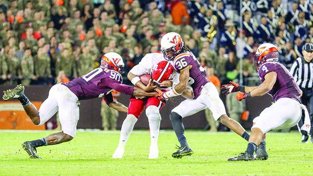 Redshirt Senior quarterback Jacoby Brissett gets hit by multiple Hokies after scrambling past the line of scrimmage. Brissett went 12 for 25 passing and 133 yards with one touchdown and one interception. The Wolfpack lost to the Hokies 28-13 at Virginia Tech in Lane Stadium on October 9th, 2015.