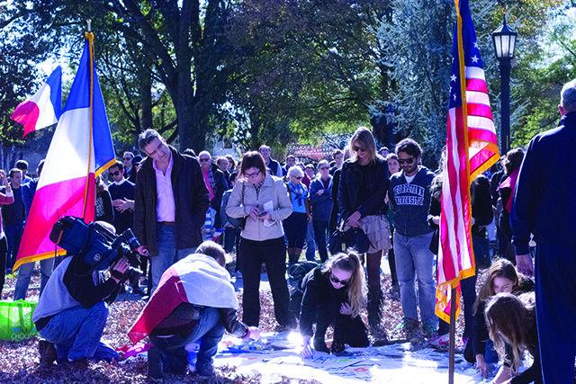 Students sign a memorial banner commemorating Justine Moulin, one of the lives lost in the recent terrorist attacks on Paris. The gathering took place on Sunday in Raleigh's historic Moore's Square.&#160;