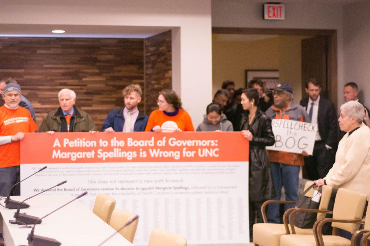 Protestors hold up a signs and a petition signed by 1,400 UNC-System faculty on Tuesday in Chapel Hill.&#160;
