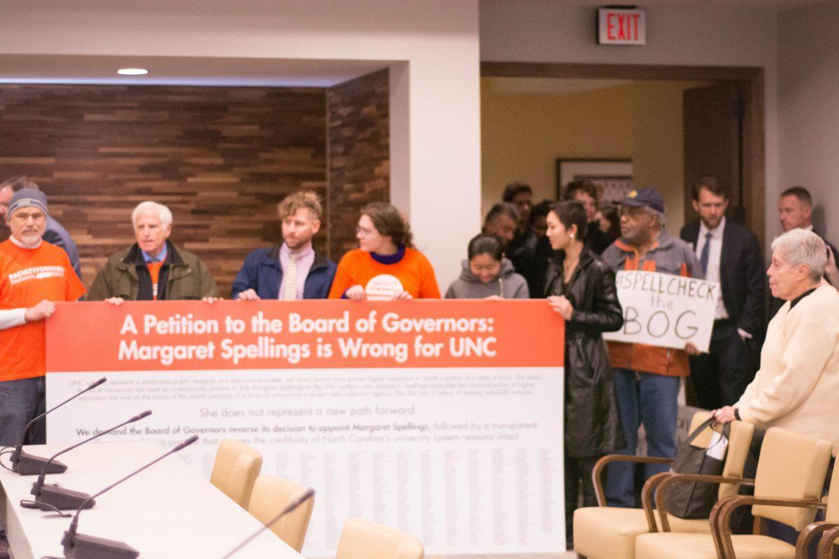 Protestors hold up a signs and a petition signed by 1,400 UNC-System faculty on Tuesday in Chapel Hill.&#160;