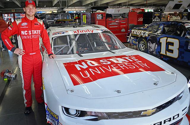 Senior Harrison Rhodes stands alongside his NC State branded racecar.&#160;