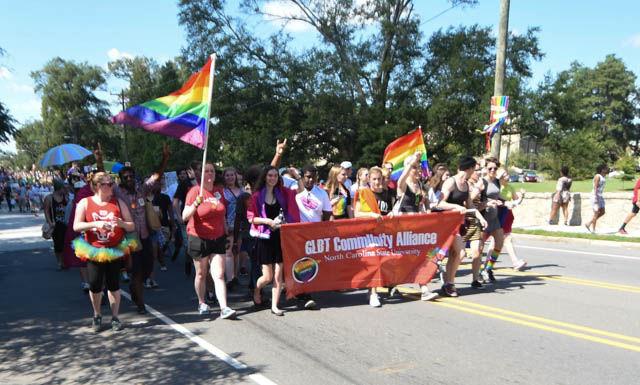 NC State students from the GLBT Community Alliance throw up wolfies at the Pride Parade held at Duke University on Saturday. Students rallied support by spreading the message of acceptance at the event.