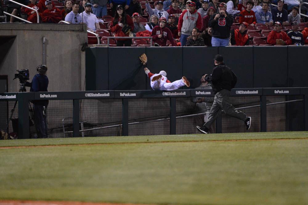 Junior infielder Evan Mendoza jumps over the ramp to try and catch the baseball April 8, 2017. Mendoza had one run, one homerun and one run batted in for three at bats in the game against Florida State. Wolfpack won 8-4 at Doak FIeld.