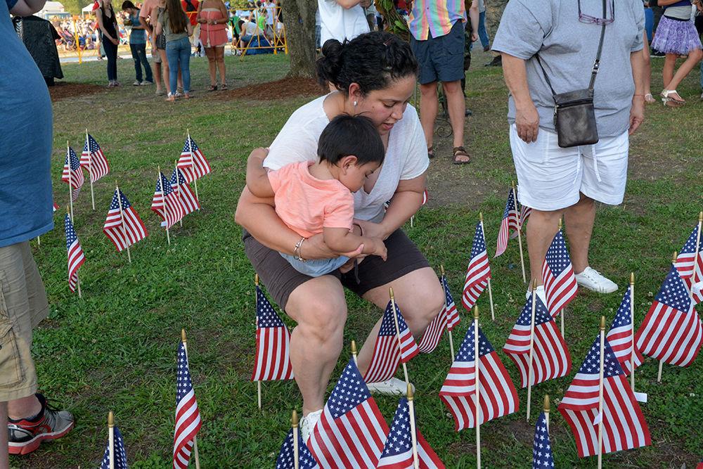 Claudia del Valle lowers her son to plant a flag in honor of veterans at the WRAL Freedom Balloon Festival on Saturday May 27, 2017 in Fuquay-Varina. The event featured more than 30 hot air balloons, food and beer vendors and live music performances.