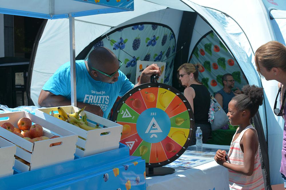 Autumn Wilson spins the wheel as volunteer Larry Reid waits to offer a healthy reward on May 20, 2017. Many people stopped by to win pears, carrots and other healthy snacks. The line stretched to the other side of the road as people waited patiently.