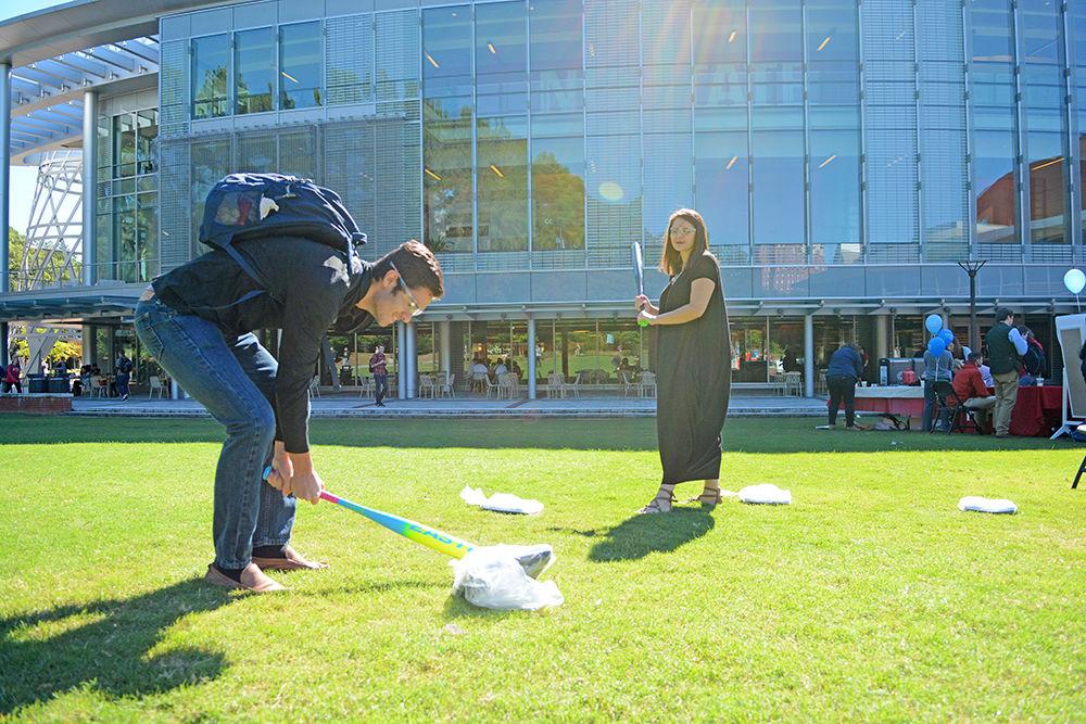 Nadeem Sheikh, a first year engineering student, smashes a scale with a baseball bat while his sister Iman Sheikh, a third year studying psychology looks on during the Southern Smash event at Stafford Commons Tuesday. McCall Dempsey, the founder of Southern Smash, created the event 5 years ago and according to her, the event is held on various campuses across the nation to promote positive body images and eating disorder awareness. Sheikh herself is recovering from an eating disorder