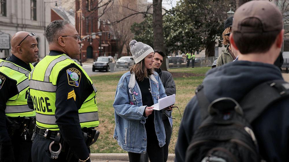 Skye McCollum, a third-year studying political science, speaks with police officers after producing an oversized sign at the Crush Confederates at the Capital event on Saturday, Feb. 9 at the North Carolina State Capitol in Raleigh.