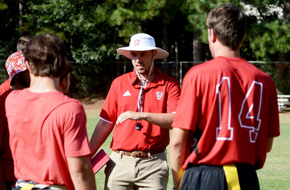Third year studying biological science and head coach Daniel Lee discusses drills with team players at practice. This the club flag football team's second year at NC State.