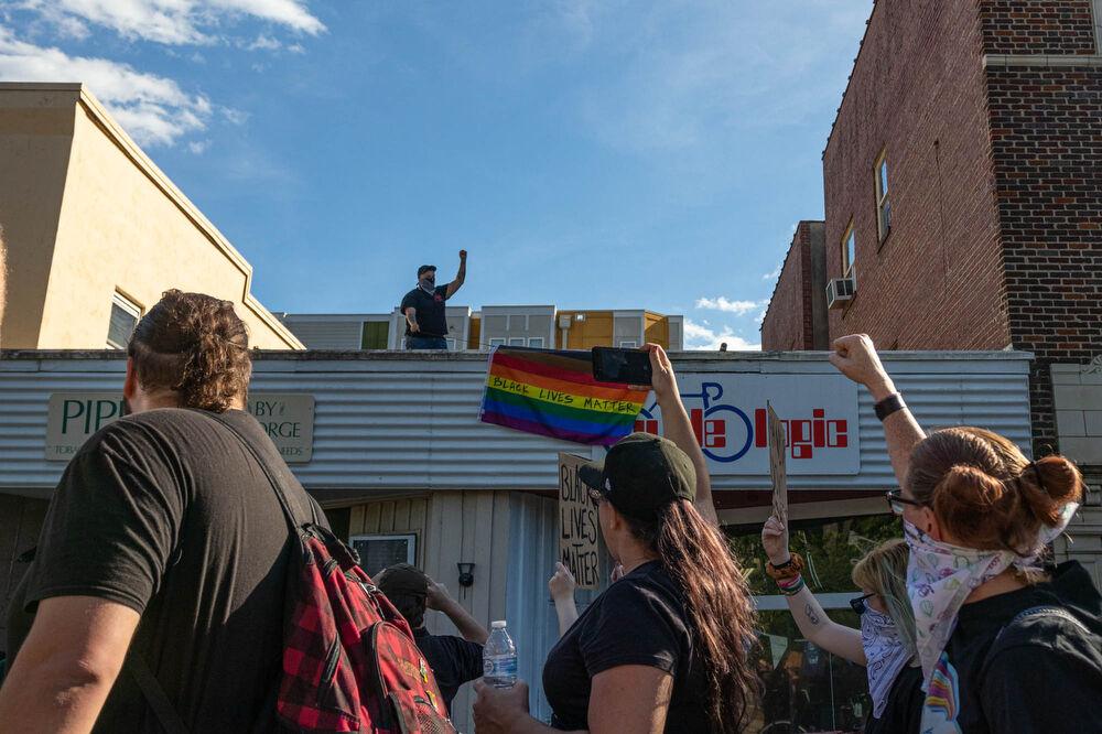 A man stands atop a roof with a pride flag with the words &#8220;Black Lives Matter&#8221; written on it on Monday, June 1, 2020 on Hillsborough street. The protest continued on from Hillsborough street into Downtown Raleigh in front of the capitol building. The protesters then marched to the governors mansion before returning back to the memorial Belltower ahead of the start of curfew at 8 P.M. Raleigh mayor, Mary-Ann Baldwin, imposed a city wide curfew until further notice from 8 P.M. until 5 A.M. the next morning. June is celebrated as pride month. The protest on June 1 was completely peaceful through its entirety.