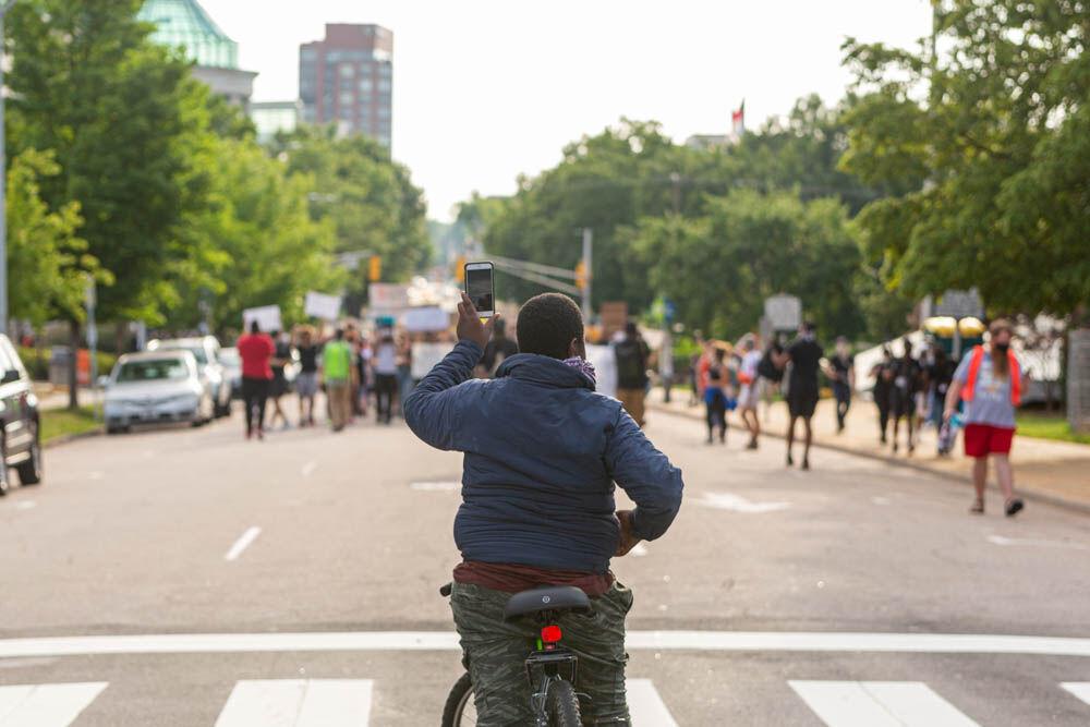 A boy on his bicycle films the protesters while they march towards the governors mansion on Tuesday, June 2, 2020 in Downtown Raleigh. The protesters walked from the Duke Energy Center, to the capitol building where they performed a die in protest and then on to the governors mansion, before returning back to the Duke Energy Center before the start of curfew.