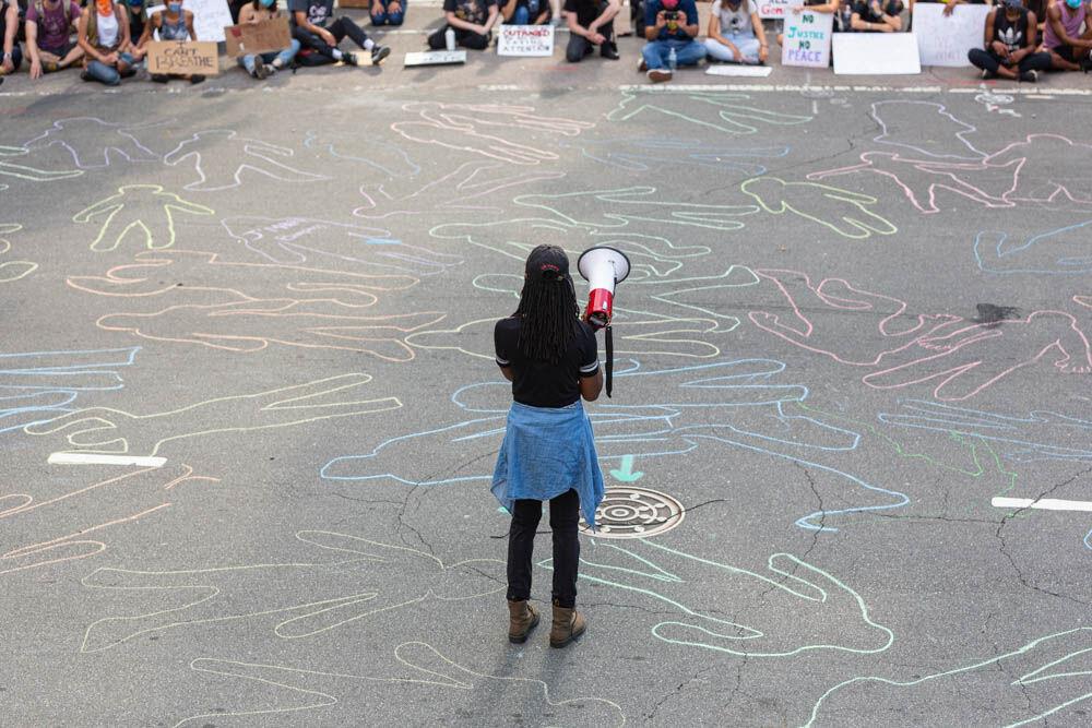A speaker stands among chalk outlines in front of the confederate monument in the capitol that represent the individuals that died as a result of police brutality on Tuesday, June 2, 2020 in Downtown Raleigh. The protesters formed as a part of the NCBORN movement and have been non-violently protesting the death of George Floyd and the Black Lives Matter movement.