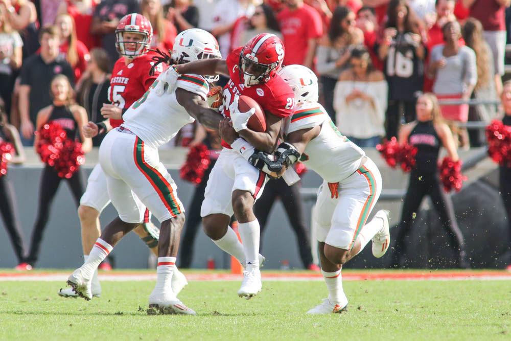 Senior running back Matt Dayes pushes through two Miami defenders for an extra yard. Dayes had 76 yards on the ground passing the 1,000 yard threshold on the season. The Wolfpack walked away with a 27-13 loss to Miami on Saturday in Carter-Finley Stadium.