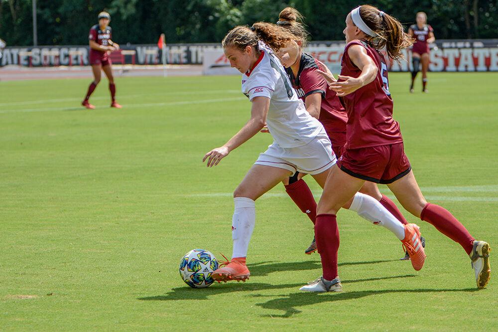 NC State freshman Annika Wohner (10) splits two defenders while on the attack during the NC State Wolfpack's game against the South Carolina Gamecocks at Dail Soccer Field on Saturday, August 29, 2021. The Wolfpack lost the match 2-1 on a last-minute score by the Gamecocks.