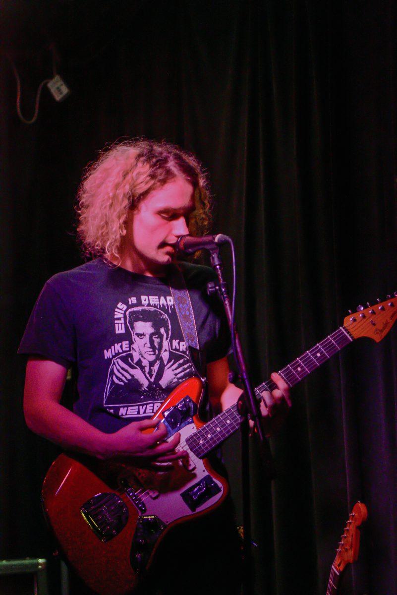 Sweet Home guitarist Rick Davis sings into the mic while playing the guitar during the first night of Double Barrel Benefit at The Pour House Music Hall on Friday, March 12, 2022. Double Barrel Benefit is an annual concert fundraiser for WKNC 88.1.