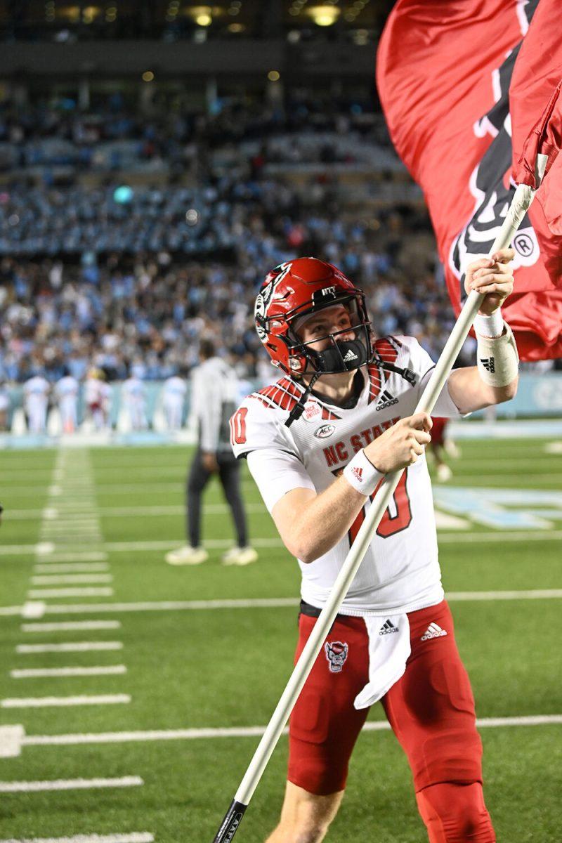 Redshirt freshman quarterback Ben Finley waves a NC State flag in celebration at midfield after the Wolfpack's last regular season football game against the UNC-Chapel Hill Tar Heels at Kenan Memorial Stadium on Friday, Nov. 25, 2022. Finley passed for two touchdowns and 271 yards as the Wolfpack beat the Tar Heels in double overtime 30-27.