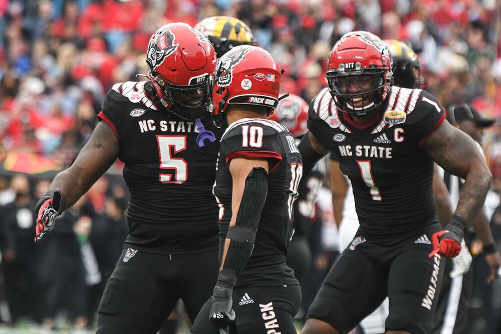 Redshirt sophomore defensive tackle C.J. Clark (left) and graduate linebacker Isaiah Moore (right) celebrate with senior safety Tanner Ingle after Ingle made a dramatic tackle during the Duke's Mayo Bowl where the NC State Wolfpack took on the Maryland Terrapins in Bank of America Stadium on Friday, Dec. 30, 2022. The Wolfpack lost to the Terrapins 16-12.