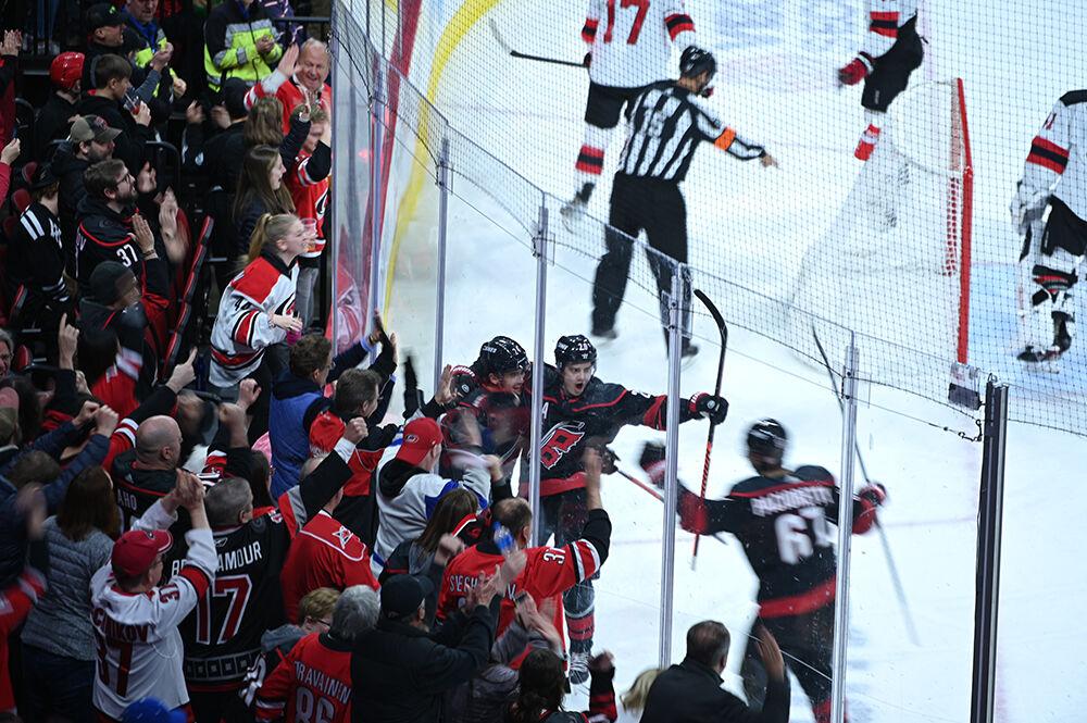 Carolina centremen Seth Jarvis and Sebastian Aho celebrate a goal against the glass with left wing Max Pacioretty during the Carolina Hurricanes' home game against the New Jersey Devils at PNC Arena on Tuesday, Jan. 10, 2023. The Canes lost to the Devils 5-3.