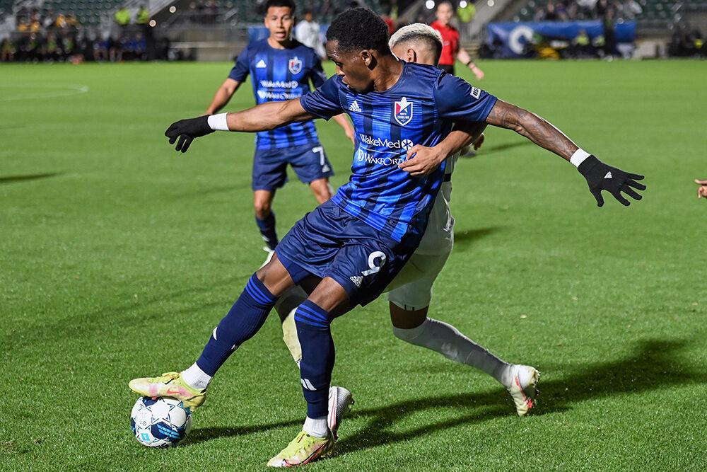 NCFC forward Oalex Anderson stops the ball as an opponent hangs on to him during the match against Lexington Sporting Club in Sahlen's Stadium at WakeMed Soccer Park on Saturday, April 1, 2023. NCFC beat Lexington SC 2-1.