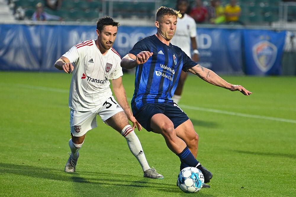 North Carolina FC forward Rafa Mentzingen dribbles the ball away from a Chattanooga Red Wolves opponent at Sahlen's Stadium in WakeMed Soccer Park on Friday, April 21, 2023. NCFC beat the Red Wolves 3-0.