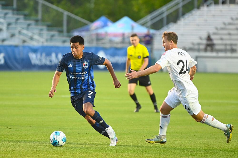 North Carolina FC midfielder Luis Arriaga dribbles the ball away from a Chattanooga Red Wolves opponent at Sahlen's Stadium in WakeMed Soccer Park on Friday, April 21, 2023. NCFC beat the Red Wolves 3-0.