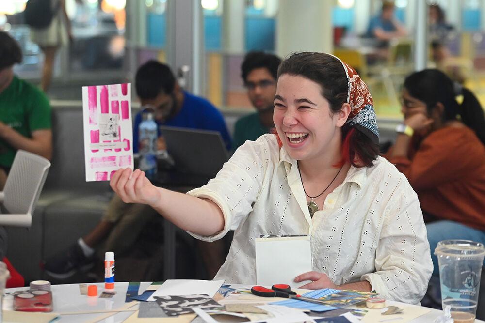 Katherine Emory, a second-year student studying political science, laughs while holding out a piece of paper during Creative Journaling at the D. H. Hill Jr. Library on Wednesday, Aug. 23, 2023. Creative Journaling, one of the events hosted during Wolfpack Welcome Week, allowed students to create and design their own journals.