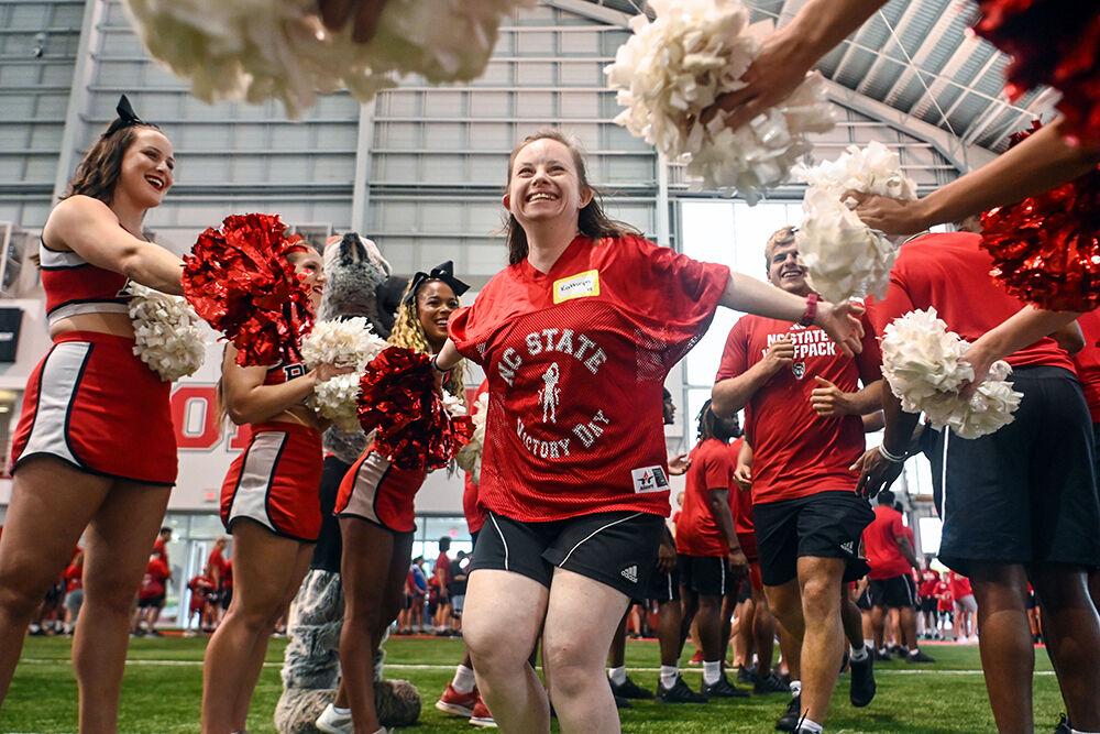 Kathryn Frye runs through a tunnel made up of NC State football players, cheerleaders and dancers during Victory Day at the Close-King Indoor Practice Facility on Friday, Aug. 4, 2023. Victory Day was an event held by GiGi's Playhouse and the NC State football team that gave young people with Down Syndrome an opportunity to run drills with players and enjoy a moment in the spotlight.