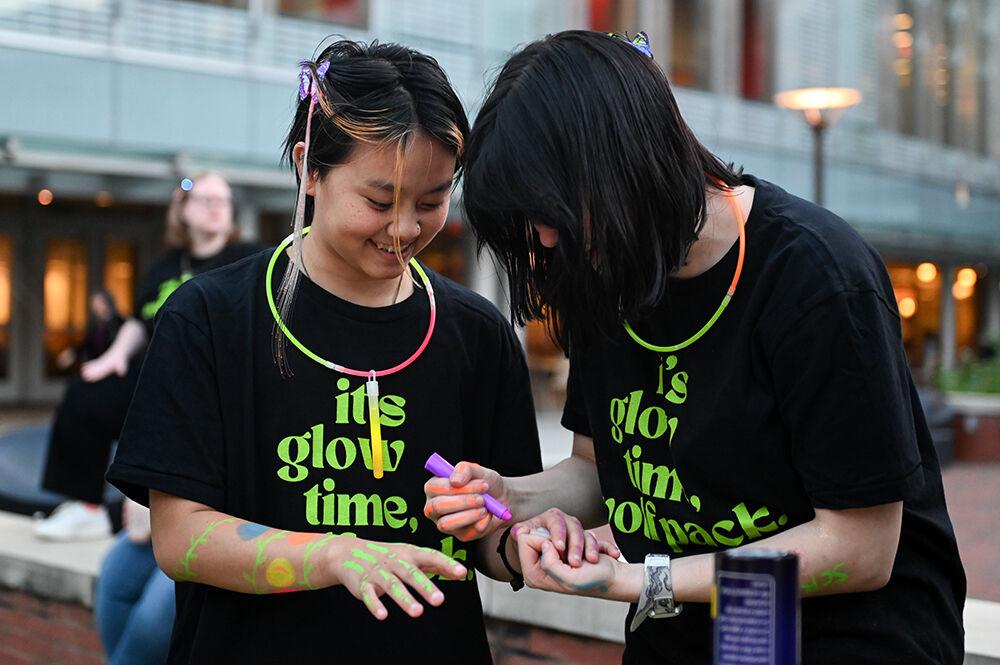 Arwen Imfeld, a first-year studying chemistry, smiles as Kelly Burger, a first-year studying aerospace engineering, draws on her arm with glow in the dark face paint during the Neon Nights event at Stafford Commons on Thursday, Nov. 9, 2023. Neon Nights was a campus walk and dance party hosted by Prevention Services to raise money for The Jed Foundation.