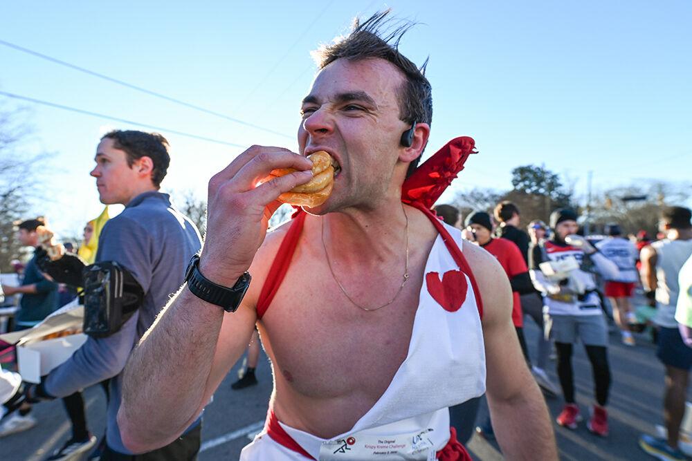 Holden Martin, dressed as cupid, devours his sandwiched donuts during the 20th Annual Krispy Kreme Challenge in Raleigh on Saturday, Feb. 3, 2024. The race challenged participants to run five miles, from the Belltower to Krispy Kreme and back again, and eat 12 donuts at the midpoint all within an hour. All proceeds from the challenge were donated to the UNC Children's Hospital.