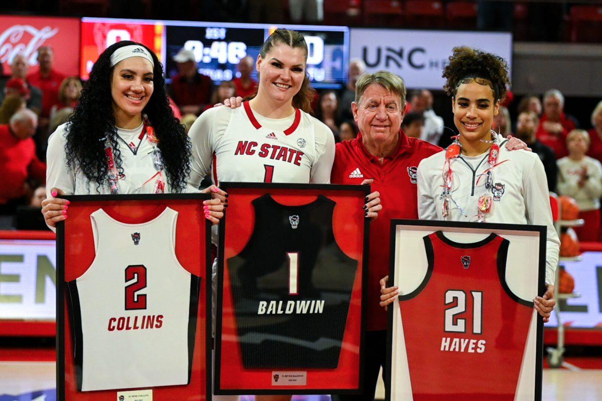 Graduate forward Mimi Colins (left), graduate center River Baldwin (middle), and senior guard Madison Hayes (right) stand with head coach Wes Moore to be recognized on Senior Day before the game against Wake Forest in Reynolds Coliseum on Sunday, March 3, 2024. NC State won against Wake Forest 75-57.