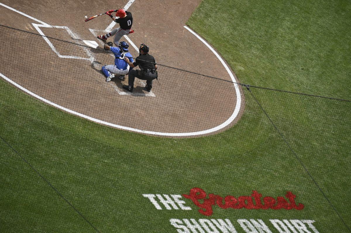 Freshman outfielder Luke Nixon bats during the College Men's World Series game between the NC State Wolfpack and the Kentucky Wildcats in Omaha, Nebraska, on Saturday, June 14, 2024. The grass on Charles Schwab field behind home plate reads 'The Greatest Show on Dirt', which is the tagline for both NCAA college world series tournaments. The Wolfpack lost to the Wildcats 5-4.