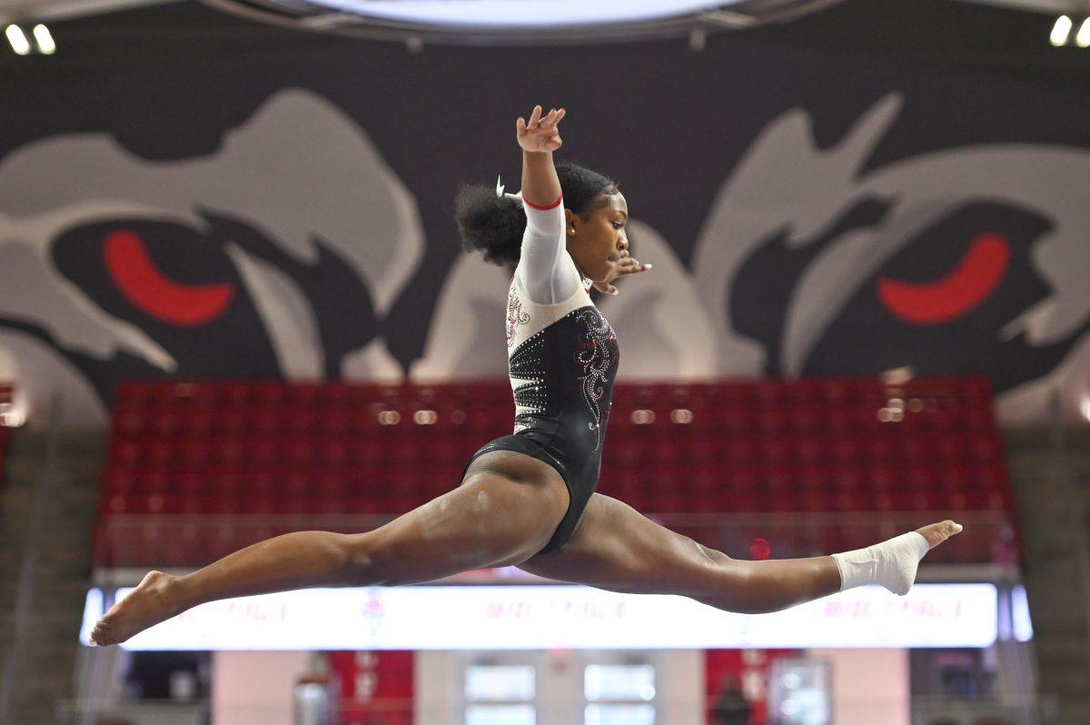 Freshman Syniya Thomas does a split leap on the balance beam during the gymnastics team's Red and White Exhibition in Reynolds Coliseum on Sunday, Dec. 15, 2024. The red team&#160;beat the white team 11-9.