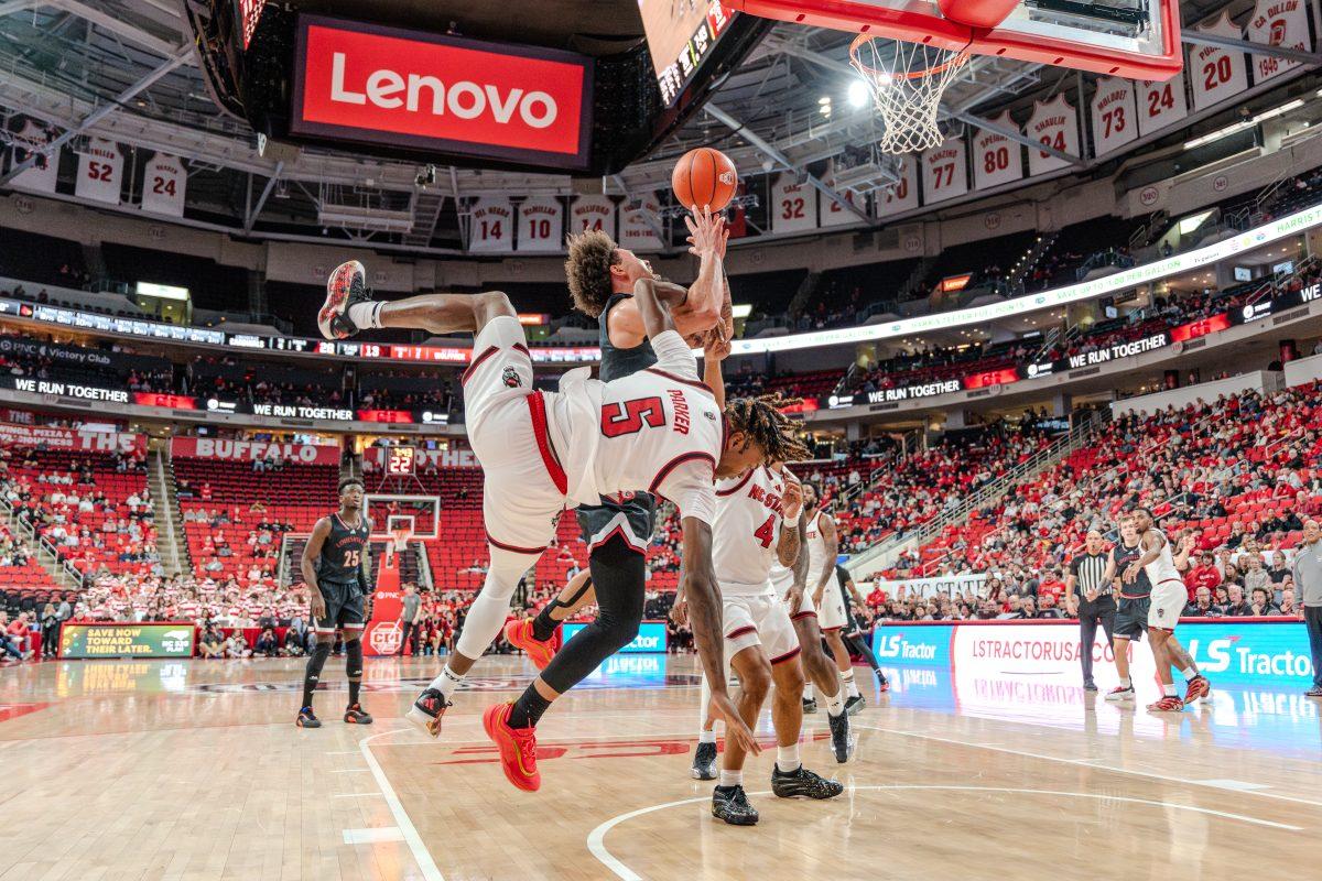 Freshman guard Trey Parker falls over his opponent during the game against University of Louisville in the Lenovo Center on Wednesday, Feb. 12, 2025. Parker scored 13 points and made one rebound.&#160;NC State lost the game 91-61.