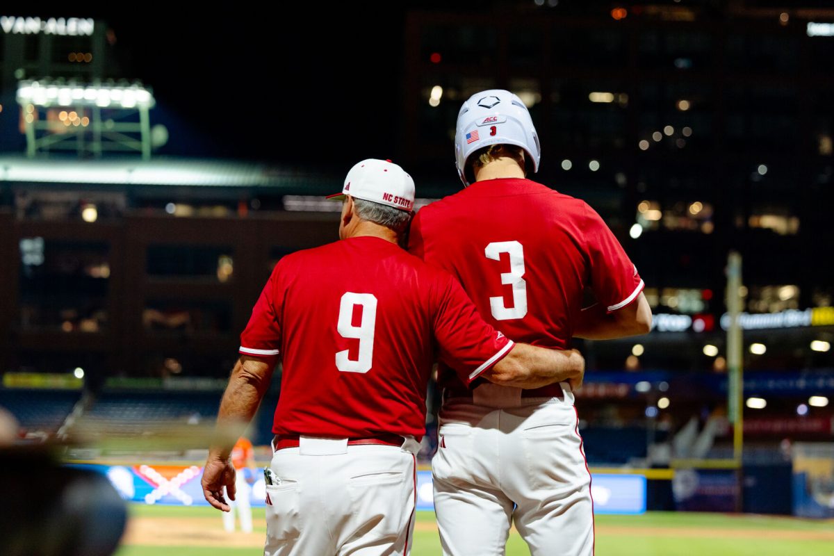 Head Coach Elliot Avent wraps his arm around freshman infielder Ryder Woodson before sending him out as a pinch runner during the quarterfinals of the ACC Baseball Tournament against Clemson at Durham Bulls Athletic Park on Thursday, May 22, 2025. NC State lost to Clemson 7-6.