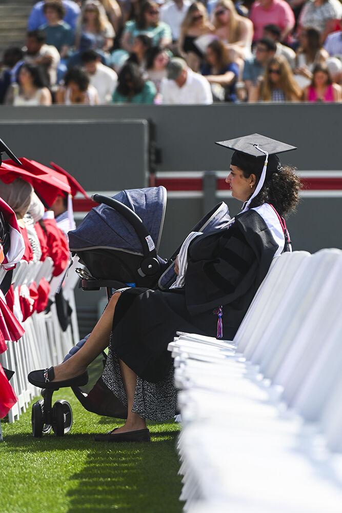 Miriam Fatnassi Nisetich, graduating with a master's degree in French, sits with her baby during the Spring Commencement Ceremony in Carter-Finley Stadium on Saturday, May 3, 2025. Nisetich was one of 1,783 students receiving their master's degrees.