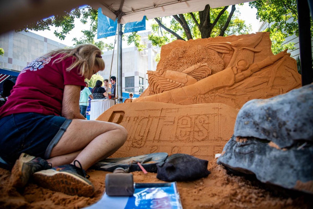 Sand sculptor Jill Harris of Sandsational Sand Sculpting etches a BugFest outline into her sand sculpture during BugFest at the North Carolina Museum of Natural Sciences on Saturday, Sept. 20, 2025. At BugFest, artists and vendors came together to visually celebrate the bug world.