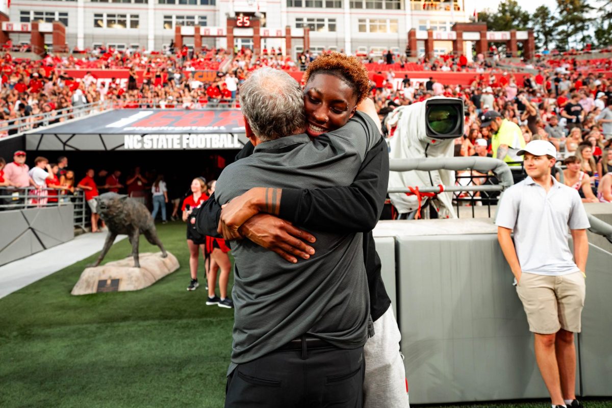 Alpha Wolf Saniya Rivers hugs Baseball head coach Elliott Avent before the game against Virginia Tech on Saturday, Sept. 27, 2025. Rivers was drafted 7th overall in the WNBA Draft by the Connecticut Sun. NC State lost to Virginia Tech 23-21.