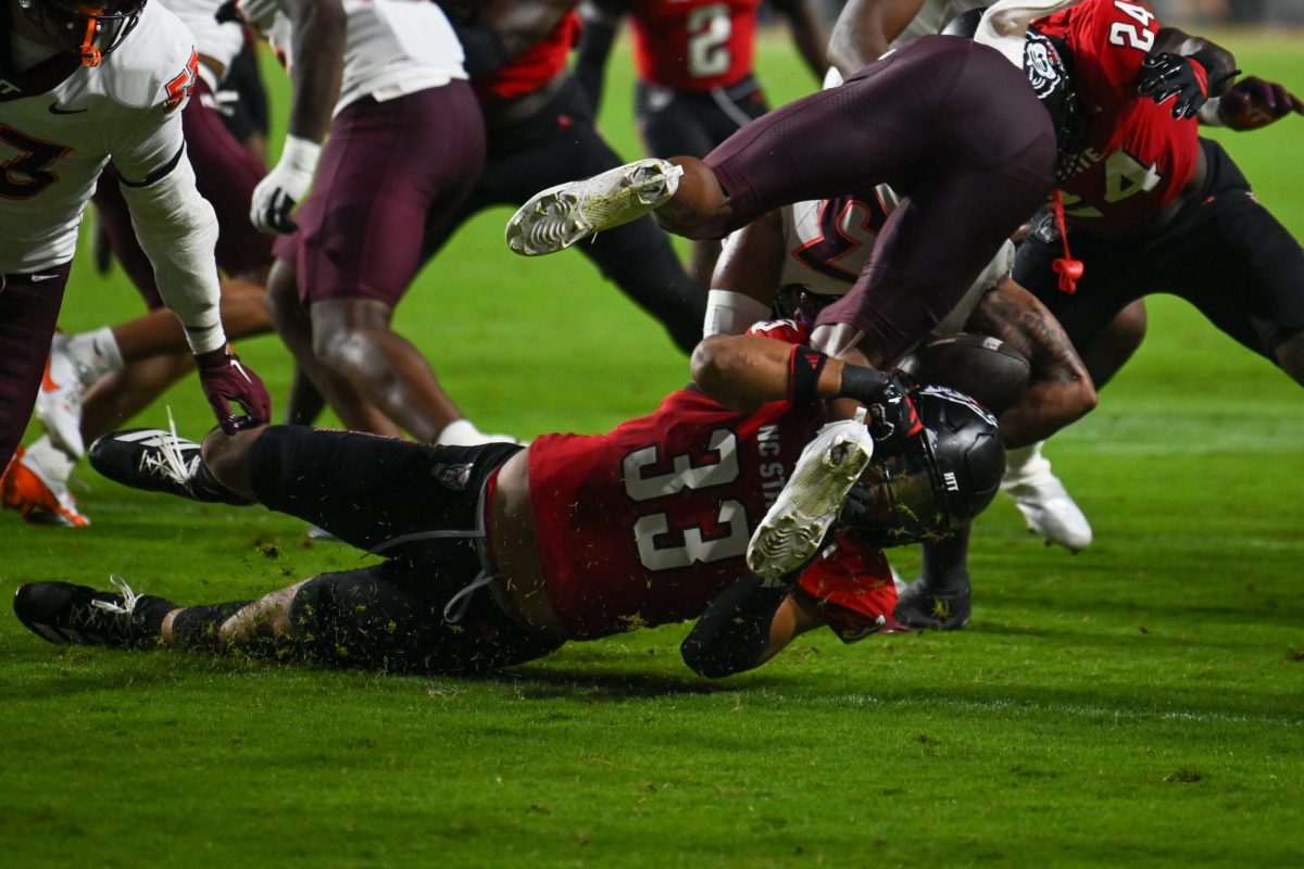 Graduate line backer Kenny Soares Jr. tackles another player during the game against Virginia Tech at Carter-Finley Stadium on Saturday, Sept. 27, 2025. Soares Jr. had two solo tackles. The Wolfpack fell to the Hokies 23-21.